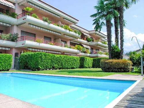 a hotel with a swimming pool in front of a building at Apartment Caslago by Interhome in Caslano