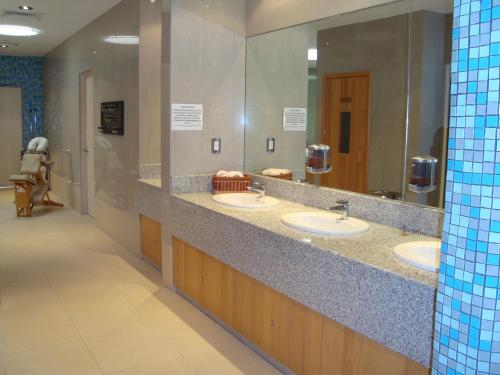 a public bathroom with three sinks and a mirror at Suites Inn la Muralla Hotel & Spa in Toluca