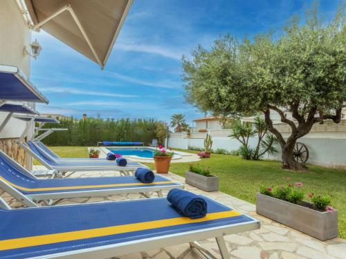 a row of blue and yellow lounge chairs next to a swimming pool at Villa Mys by Interhome in Miami Platja