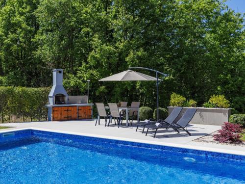a swimming pool with two chairs and an umbrella next to a swimming pool at Apartment Eroa by Interhome in Žminj