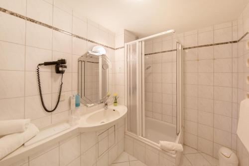 a white bathroom with a shower and a sink at Montana Hotel in Oberasbach