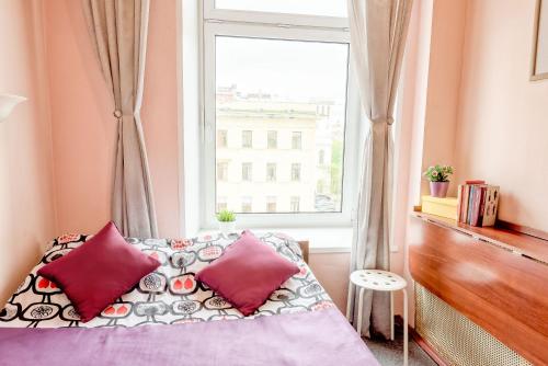 Schlafzimmer mit einem Bett mit roten Kissen und einem Fenster in der Unterkunft WonderHostel on Nevsky 23 in Sankt Petersburg