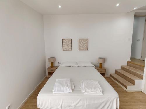 a white bedroom with a large bed with two pillows at Ca Na Margalida in Muro