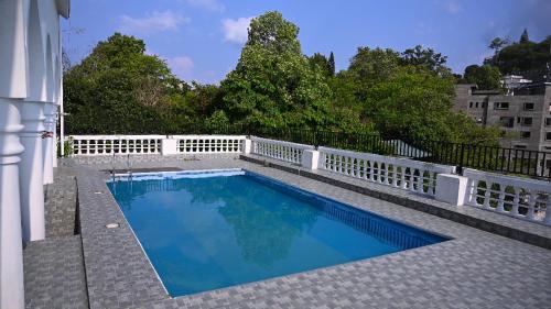 a swimming pool next to a white fence at Aijal Club in Āīzawl