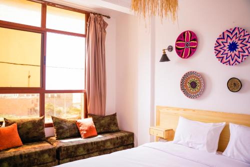 a bedroom with a bed and a couch and a window at Salty Life Surf House in Imsouane