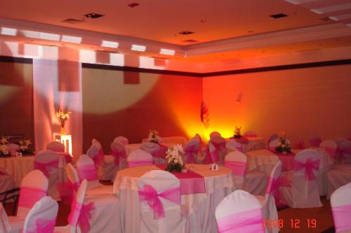 a banquet hall with white tables and chairs with pink bows at Amérian Hotel Casino Gala in Resistencia