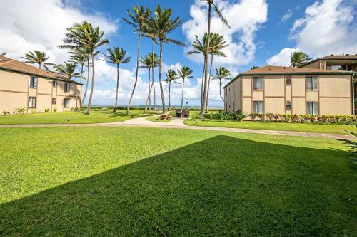 a lawn in front of a building with palm trees at 2 Bedroom OceanView Condo Pono Kai Resort E103 in Kapaa