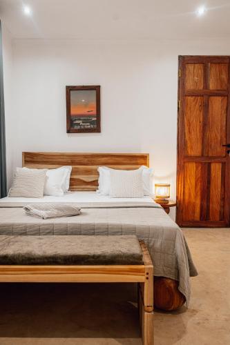a bedroom with a large bed and a wooden door at Nyumbani Stonetown in Zanzibar City