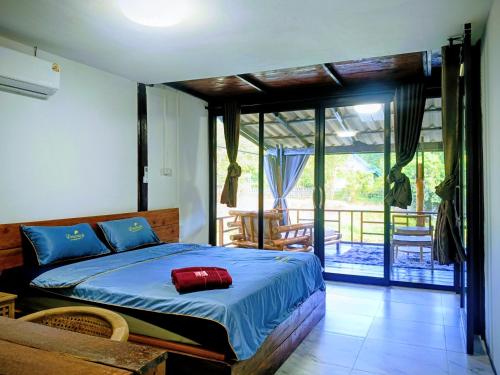 a bedroom with a bed with blue sheets and a balcony at Lake side villa in Ko Phangan