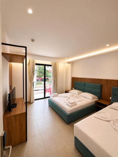 a hotel room with two beds and a television at Prestige Hotel in Ksamil