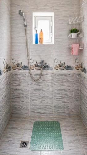 a bathroom with a shower with a green mat at Asraf village guesthouse in Aydar Kul’