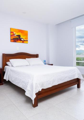 a bedroom with a large bed with white sheets at Sanha Plus Hotel in Santa Marta