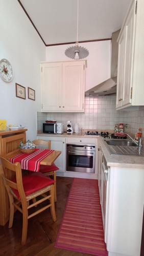 a kitchen with white cabinets and a red rug at Appartamento Storico a Palmanova in Palmanova