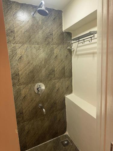 a bathroom with a shower with a stone wall at TriboRoots Hostel in Anjuna