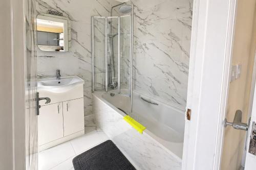 a white bathroom with a shower and a sink at Nayla House Cozy 4BR with Garden & Parking in Moffat