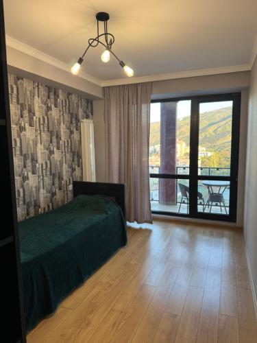 a bedroom with a green bed and a large window at monolit residens 6C blok in Tbilisi City