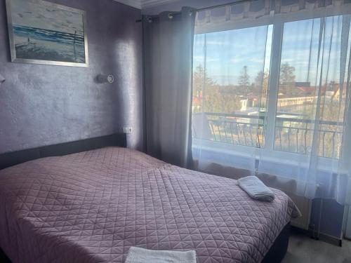 a bedroom with a bed and a large window at MARMAT Łeba in Łeba