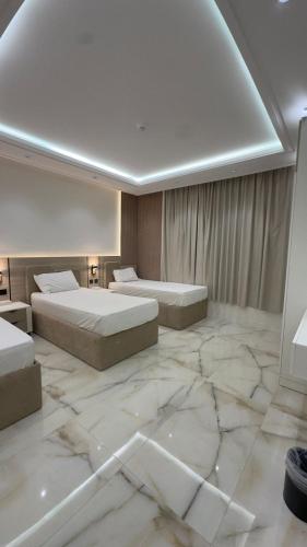 a hotel room with two beds and a marble floor at شاليهات الحدبان - Al Hadban Chalets in Ash Shafa