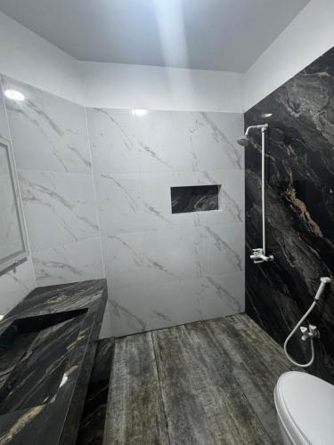 a bathroom with a marble shower and a toilet at Seaview lodge Executive in Karachi