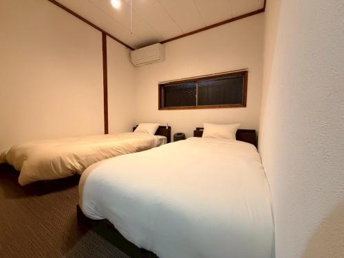 a room with two beds and a window at ura San Jose ツインルーム in Okayama