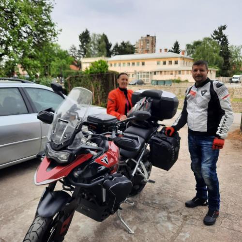 two men are standing next to a motorcycle at AGAPE in Leskovac