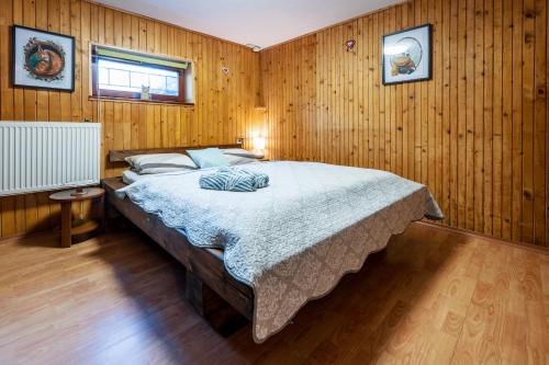 a bedroom with a large bed in a wooden wall at Squirrel cottage Chata Veverica in Dolná Lehota