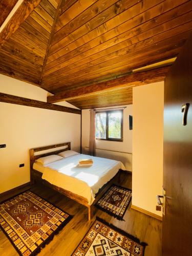 a bedroom with a bed and a wooden ceiling at Pensiunea Ioana in Borşa