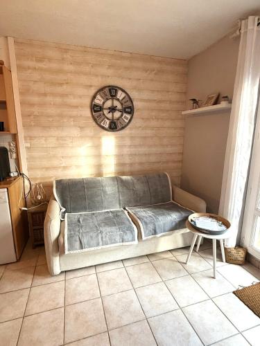 a living room with a couch and a clock on the wall at Studio cosy les Sables d'Or in La Guérinière