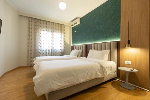 two beds in a room with a green board on the wall at Hotel Vila e Arte City Center in Tirana