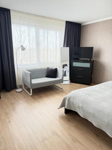 a bedroom with a bed and a chair and a television at Vienibas apartment in Daugavpils