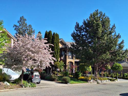 a car parked in front of a house with trees at Villa Bellissimo FranTállia - Beautéssera & Galleríseum in Kelowna