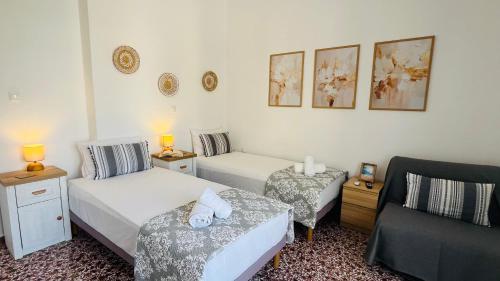 a bedroom with two beds and a couch and a chair at Elina's Rooms in Poros