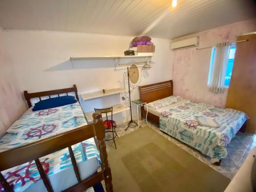 a small room with two beds and a desk at Hospedagem Mandala in Ubatuba
