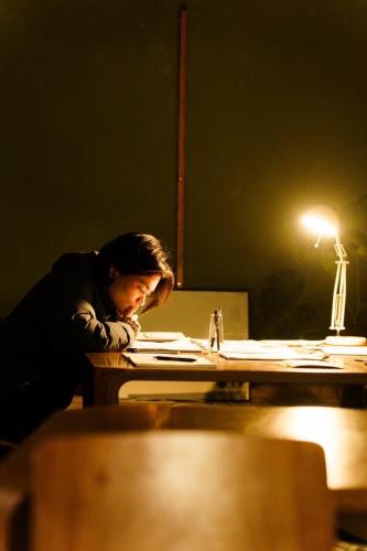 a man sitting at a desk in a dark room at Local Knot Backpackers in Nagano