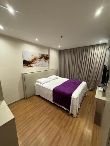 a bedroom with a large bed with a purple blanket at LUXO Premium Studio Pelinca in Campos dos Goytacazes