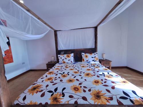 a bedroom with a bed with a floral comforter at Bwereusunsetbungalow in Kidoti