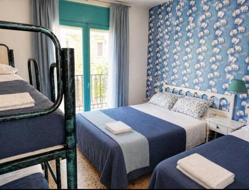 a bedroom with two beds and a blue wall at Camino de Santiago Can Pau Costa Brava in Llança