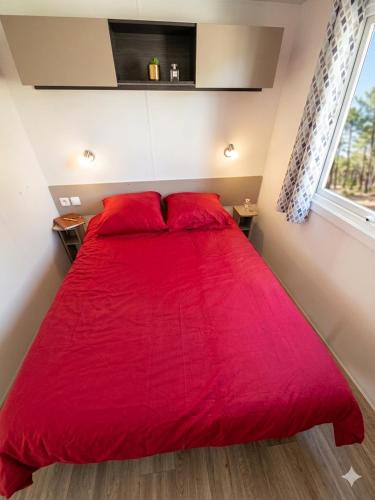 a red bed with red pillows in a bedroom at Les sables du midi in Valras-Plage
