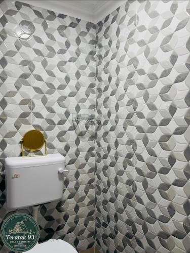 a bathroom with a toilet and a tiled wall at Teratak 93 in Karak