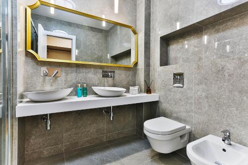 a bathroom with two sinks and a toilet and a mirror at Poljana Olive Homes Pool Residences in Rijeka Reževići