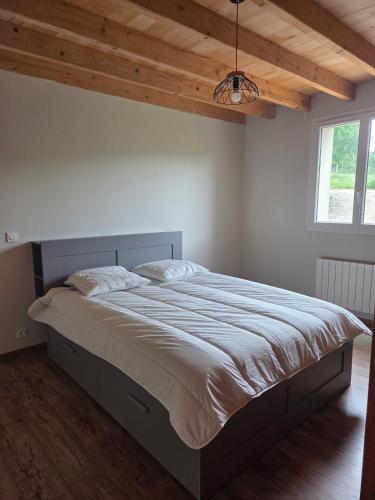 a large bed in a bedroom with a wooden ceiling at Maison de campagne in Eymet