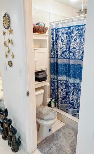 a bathroom with a toilet and a blue shower curtain at Studio Bella in Philipsburg