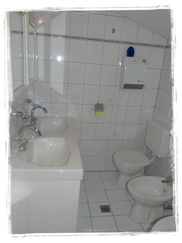 a white bathroom with a sink and a toilet at Ferienwohnungen am Bauernhof in Rangersdorf