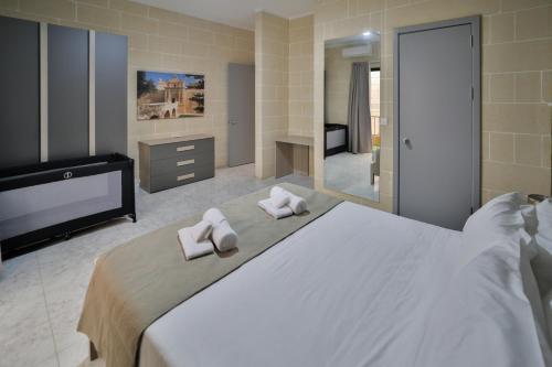 a bedroom with a large white bed with towels on it at Hot Tub With View, Stylish 3BR, Heart of Ghajnsielem in Għajnsielem