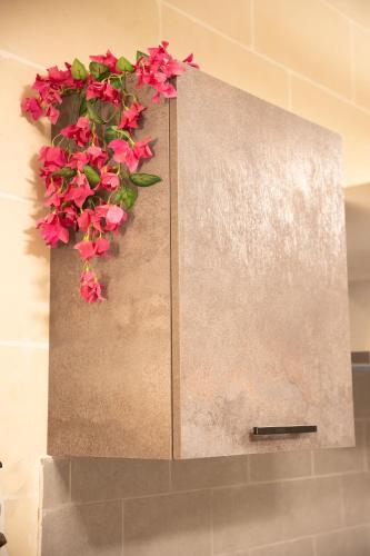 a planter with pink flowers on a wall at Hot Tub With View, Stylish 3BR, Heart of Ghajnsielem in Għajnsielem