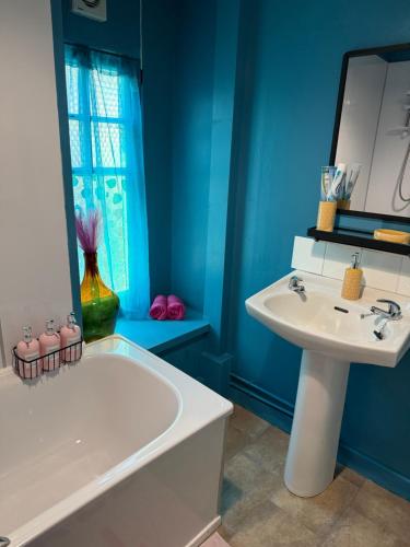 a blue bathroom with a tub and a sink and a tubermott at Well St Apartment in Moffat