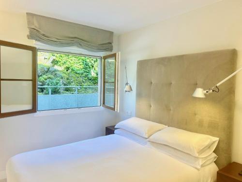 a bedroom with a white bed and a window at Tu lugar en la playa in Luanco