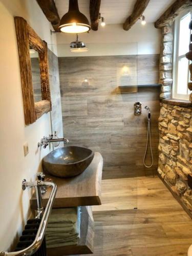a bathroom with a sink and a stone wall at Unique Accommodation in Twente with Jacuzzi in Borne