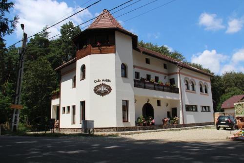 un bâtiment blanc doté d'une tour d'horloge. dans l'établissement Casa Marta, à Sîmbăta de Sus