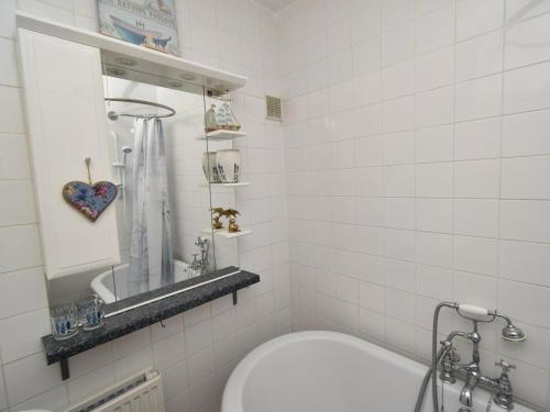 a white tiled bathroom with a toilet and a sink at 1 Bed in Goodwick oc-fb274 in Goodwick
